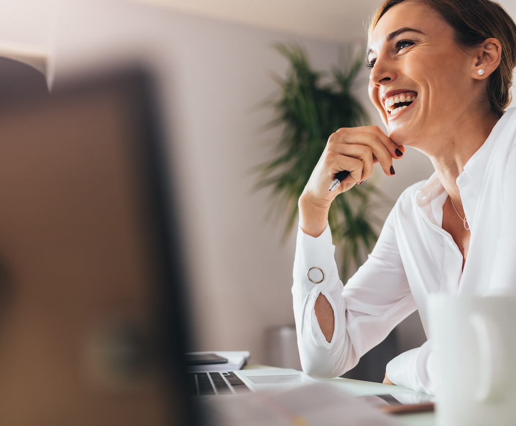 Smiling,Woman,Sitting,At,Her,Desk,In,Office.,Happy,Business